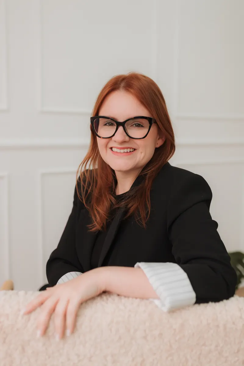 Patricia, fundadora da Nursy, sorrindo, debruçada em uma poltrona clara